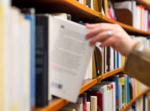 pulling a book from the shelf at the bookstore. A customer buying a book at a bookstore.